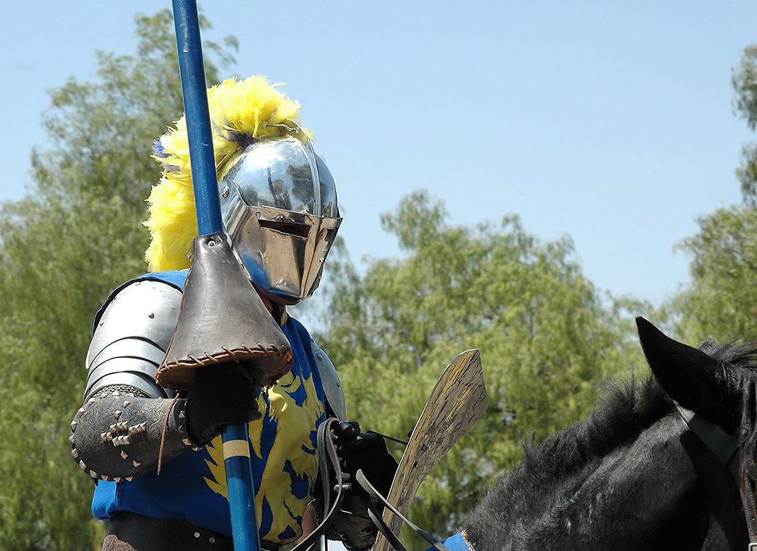 About Our Agency - Closeup Portrait of a Medieval Knight in Armor Holding a Lance While Riding on a Black Horse at the Renaissance Faire