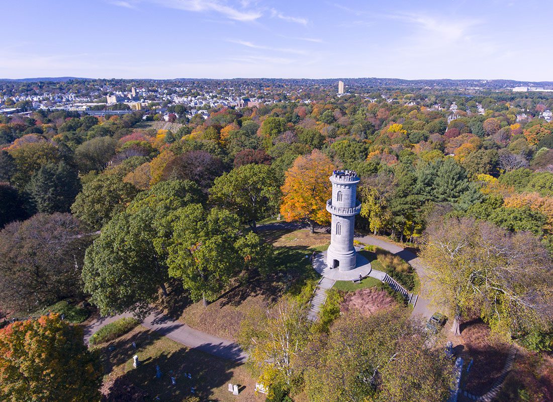 Auburn, MA - Aerial View of a Cemetery with Colorful Fall Foliage Surrounding a Medieval Looking Stone Tower in Auburn Massachusetts