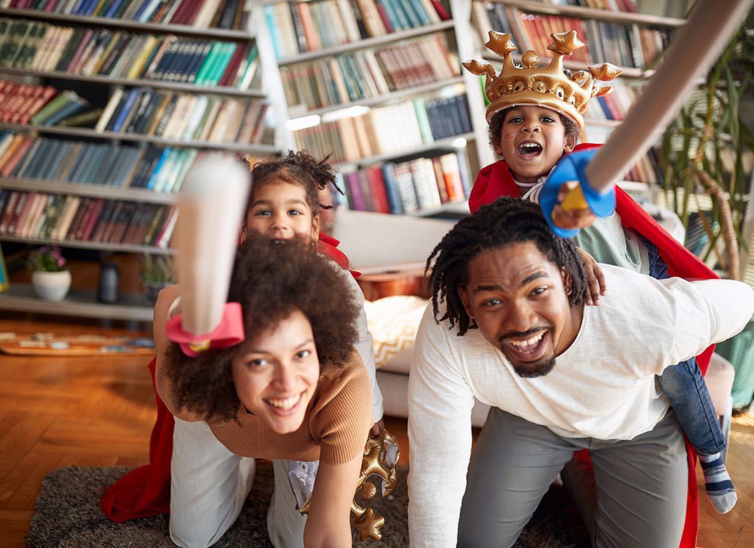 Contact - Cheerful Parents Having Fun Playing Make Believe with Their Children Holding Toy Swords in Costumes